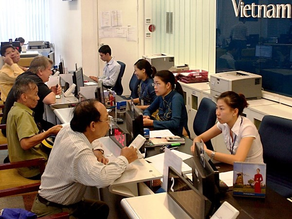 Khách hàng mua vé tại đại lý vé máy bay của Vietnam Airlines. (Ảnh: Huy Hùng/TTXVN) Hành khách được lợi gì khi Vietnam Airlines nâng cấp dịch vụ 4 sao? ảnh 2