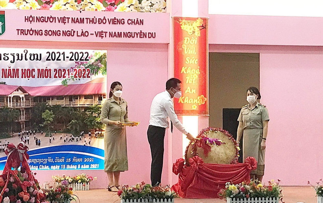 Bí thư thứ nhất Đại sứ quán Việt Nam tại Lào Trần Đại Thắng và Hiệu trưởng Trường song ngữ Lào-Việt Nam Nguyễn Du Sivanheuang Phengkhammay đánh trống khai giảng năm học mới 2021-2022. (Ảnh: Thu Phương/TTXVN) Trường song ngữ Lào-Việt Nam Nguyễn Du khai giảng năm học 2021-2022 ảnh 1