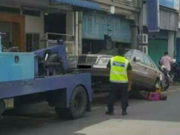 Người đàn ông nằm dưới bánh xe Mercedes để ngăn cản chiếc xe bị kéo đi. (Nguồn: Nst.com.my) Dùng thân mình ngăn cảnh cảnh sát giao thông kéo xe đi ảnh 1