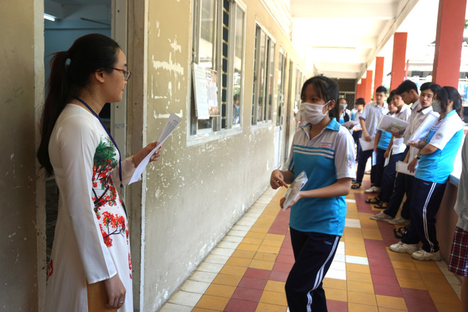 Cán bộ coi thi kiểm tra thông tin thí sinh trước khi vào phòng thi tại điểm thi Trường THPT Thủ Đức. (Ảnh: Thu Hoài/TTXVN) TP.HCM: Hơn 85.000 thí sinh làm thủ tục dự thi tốt nghiệp THPT ảnh 1