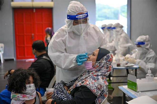 Nhân viên y tế lấy mẫu xét nghiệm COVID-19 cho người dân tại Kuala Lumpur, Malaysia. (Ảnh: AFP/TTXVN) Malaysia tiếp tục ghi nhận hàng nghìn ca mắc COVID-19 mới ảnh 1