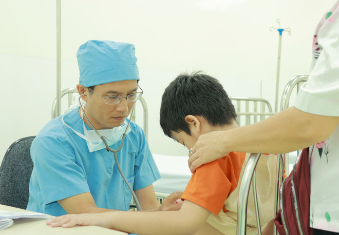 Tiến sỹ, bác sỹ Đỗ Nguyên Tín khám bệnh cho trẻ em mắc bệnh tim bẩm sinh. (Ảnh: Đinh Hằng/TTXVN) ttxvn_do nguyen tin (2).jpg