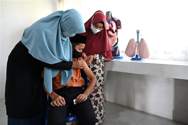 Nhân viên y tế tiêm vaccine phòng COVID-19 cho học sinh tại Darul Imarah, gần Banda Aceh, Indonesia. (Ảnh: AFP/TTXVN) Indonesia ghi nhận các ca đầu tiên nhiễm biến thể phụ của Omicron ảnh 1