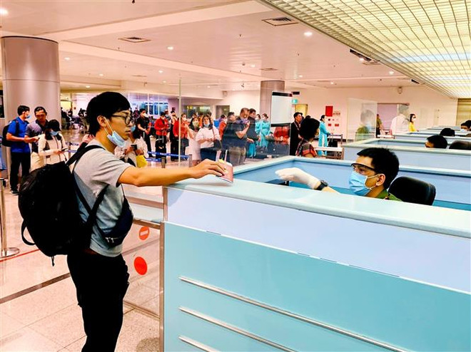 Cán bộ công an cửa khẩu Tân Sơn Nhất chủ động trang bị đầy đủ khẩu trang, găng tay trong khi làm nhiệm vụ. (Ảnh: Thành Chung/TTXVN) Bắt buộc người nhập cảnh từ Hàn Quốc phải khai báo y tế từ 23/2 ảnh 1