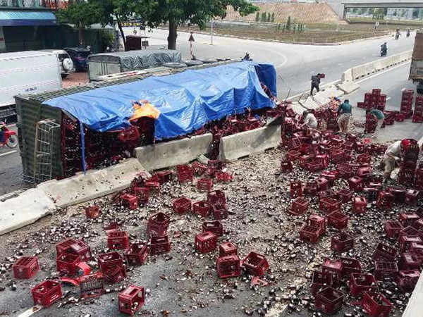 Xe đầu kéo bị lật, hàng trăm két bia rơi xuống Quốc lộ 1A ảnh 1