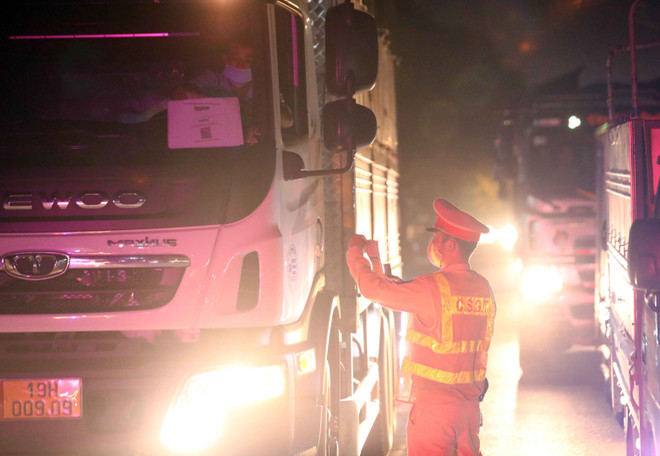 Lực lượng CSGT kiểm tra giấy tờ các phương tiện giao thông đăng ký luồng xanh trước khi di chuyển vào Hà Nội. (Ảnh: Phạm Kiên/TTXVN) Đề nghị địa phương hỗ trợ vận tải hàng hóa theo chỉ đạo của Chính phủ ảnh 1