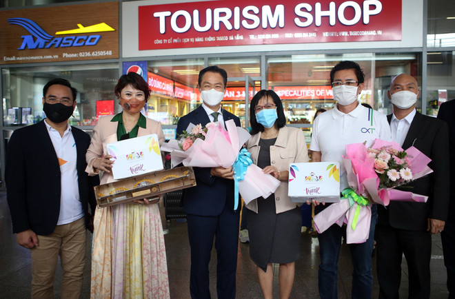 Phó Giám đốc Trung tâm Xúc tiến Du lịch Đà Nẵng Huỳnh Thị Hương Lan (giữa) tặng hoa và quà lưu niệm cho đại diện đoàn khách MICE. (Ảnh: Trần Lê Lâm/TTXVN) Thành phố Đà Nẵng đón đoàn 720 khách du lịch MICE ảnh 2