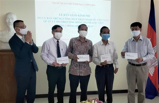 Đại sứ Vũ Quang Minh (bên trái) bàn giao kinh phí các cơ quan đại diện tại Campuchia và Hội Khmer-Việt Nam tại Campuchia. (Ảnh: Ngọc Long/TTXVN) Bàn giao khoản hỗ trợ 85.000 USD giúp người gốc Việt tại Campuchia ảnh 1
