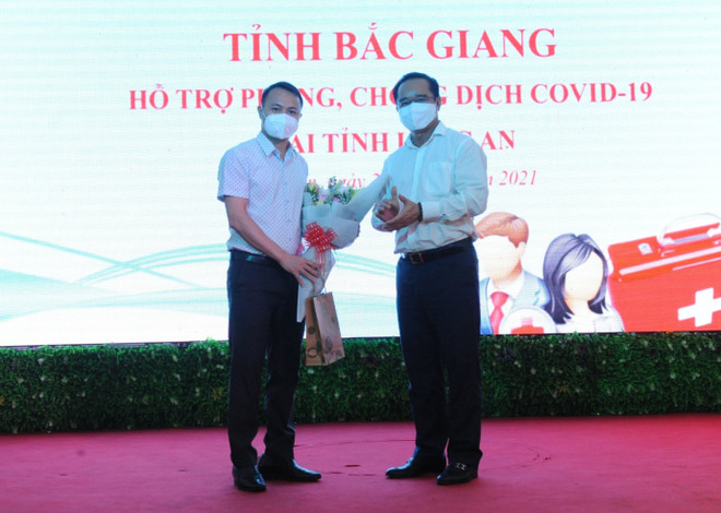 Bí thư tỉnh ủy Long An Nguyễn Văn Được tặng hoa Thạc sỹ Đặng Văn Hòa, Trưởng đoàn Y tế tỉnh Bắc Giang. (Ảnh: Thanh Bình/TTXVN) Hơn 100 cán bộ y tế Bắc Giang, Hòa Bình hỗ trợ các tỉnh phía Nam ảnh 1