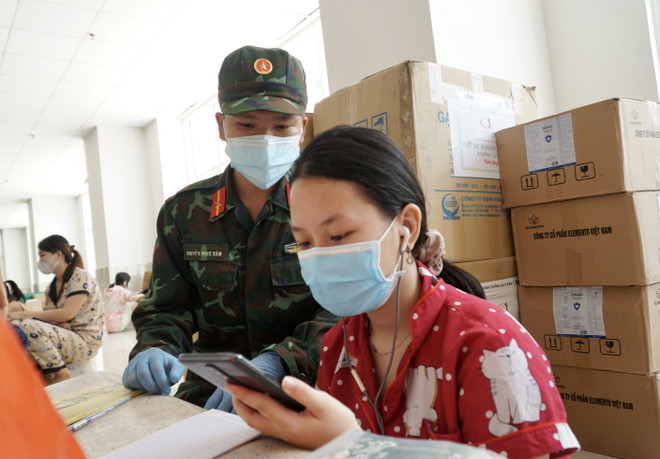Cán bộ, chiến sỹ hỗ trợ các em học trực tuyến tại lớp học dã chiến ở chung cư 1050 (quận Bình Thạnh). (Ảnh: Thu Hương/TTXVN) TP.HCM đồng hành với học sinh vượt khó khăn do dịch COVID-19 ảnh 1
