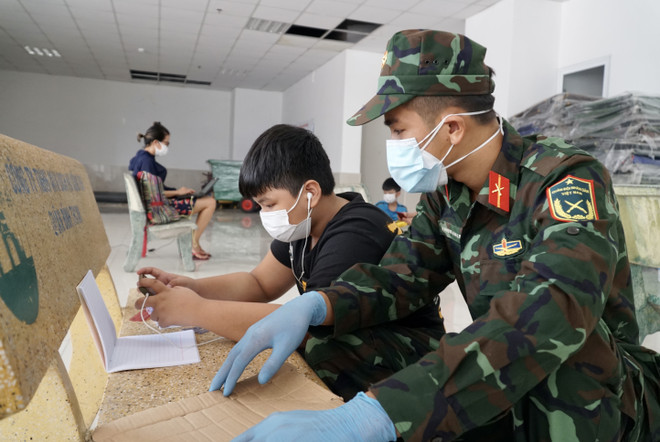 Cán bộ, chiến sỹ hỗ trợ các em học trực tuyến tại lớp học dã chiến ở chung cư 1050 (quận Bình Thạnh). (Ảnh: Thu Hương/TTXVN) TP.HCM đồng hành với học sinh vượt khó khăn do dịch COVID-19 ảnh 3