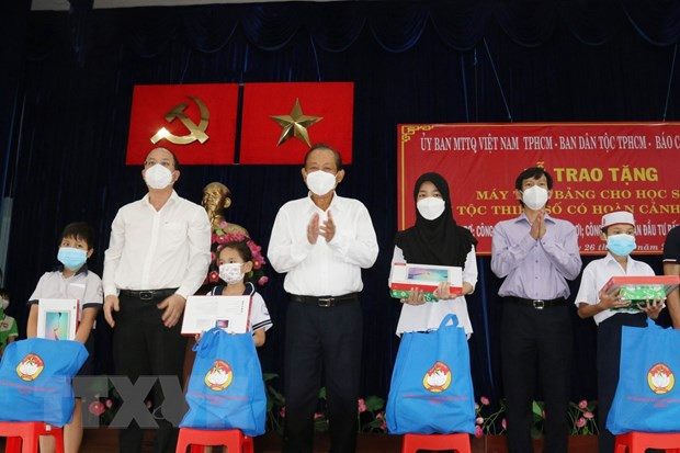 Ông Trương Hòa Bình, nguyên Ủy viên Bộ Chính trị, nguyên Phó Thủ tướng Thường trực Chính phủ, và ông Nguyễn Hồ Hải, Phó Bí thư Thành ủy Thành phố Hồ Chí Minh (thứ 2 từ trái sang) trao tặng máy tính bảng cho các học sinh dân tộc Chăm và Khmer. (Ảnh: Xuân Khu/TTXVN) Đảm bảo quyền học tập của trẻ em bị ảnh hưởng do dịch COVID-19 ảnh 1