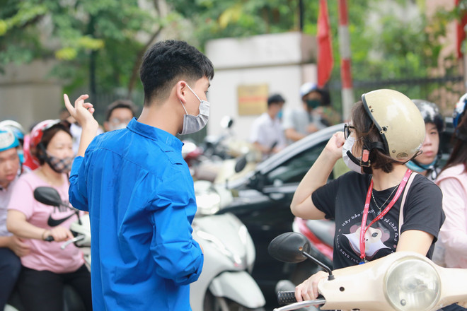 Thanh niên tình nguyện hỗ trợ các lực lượng chức năng phân làn, giữ trật tự quanh điểm thi. (Ảnh: PV/Vietnam+) Tuổi trẻ Thủ đô ra quân tiếp sức cho các sỹ tử trong kỳ thi vào lớp 10 ảnh 5