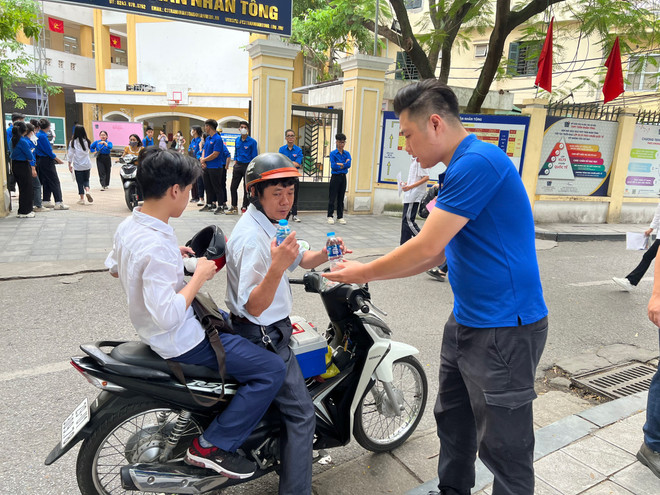 'Chiến binh áo xanh' hỗ trợ nước lọc cho phụ huynh, học sinh tại điểm thi trường Trung học phổ thông Trần Nhân Tông (quận Hai Bà Trưng). (Ảnh: PV/Vietnam+) Tuổi trẻ Thủ đô ra quân tiếp sức cho các sỹ tử trong kỳ thi vào lớp 10 ảnh 2