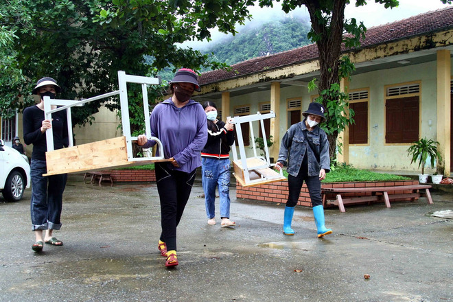 Cán bộ giáo viên trường Tiểu học Tân Hóa (huyện Minh Hóa, Quảng Bình) vận chuyển, kê lại bàn ghế lớp học sau khi nước rút. (Ảnh: Tá Chuyên/TTXVN) TTXVN_2109 Quang Binh khac phuc bao lu 1.jpg