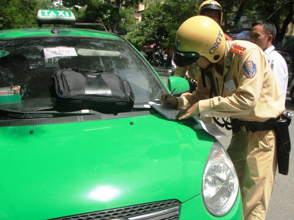 Cảnh sát giao thông xử phạt xe taxi vi phạm Luật giao thông. (Ảnh: Việt Hùng/Vietnam+) Hà Nội "dẹp loạn" taxi trước thời điểm Tết Nguyên đán ảnh 1