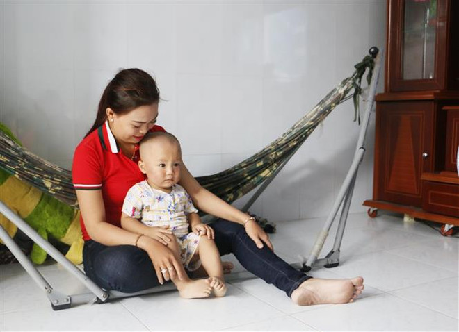 Cháu Nguyễn Quốc Huy đang được mẹ chăm sóc tại gia đình. (Ảnh: Phạm Minh Tuấn/TTXVN) Vĩnh Long: Làm rõ sự việc bé trai 19 tháng tuổi bị bảo mẫu tát ảnh 1