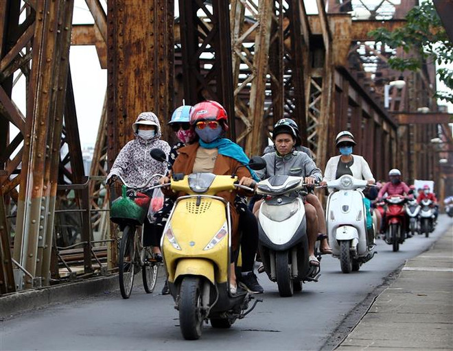 Người dân với trang phục áo ấm đi trên cầu Long Biên (Hà Nội). (Ảnh: Danh Lam/TTXVN) Hà Nội chuyển mưa rét từ chiều tối 23/12, nhiệt độ xuống 16 độ C ảnh 1