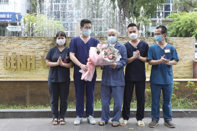 Êkíp bác sỹ, điều dưỡng điều trị ca bệnh của Bệnh viện Thanh Nhàn tặng hoa chúc mừng bệnh nhân H.V.N (giữa) khỏi bệnh, ra viện ngày 17/9. (Ảnh: Minh Quyết/TTXVN) Hà Nội: Bệnh nhân mắc COVID-19 nặng được chữa khỏi bằng kỹ thuật ECMO ảnh 1
