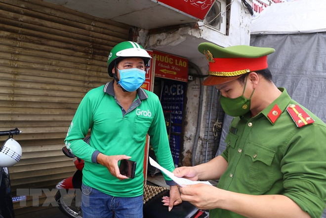 Công an phường Bạch Mai (quận Hai Bà Trưng) kiểm tra, hướng dẫn lái xe công nghệ thực hiện nghiêm túc Chỉ thị 17/CT-UBND của Ủy ban Nhân dân Thành phố Hà Nội. (Ảnh: Hoàng Hiếu/TTXVN) Hà Nội: Sẽ xử phạt 'shipper' ra đường không có lý do chính đáng ảnh 1