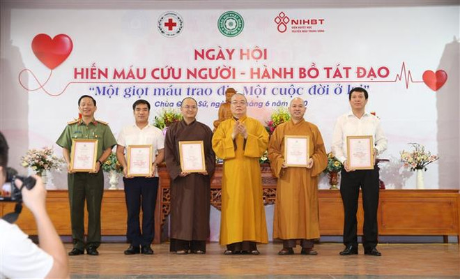 Hòa thượng Thích Thanh Nhiễu, Phó Chủ tịch Thường trực Hội đồng Trị sự GHPG Việt Nam trao tặng Giấy chứng nhận hiến máu cho các đơn vị tại ngày hội. (Ảnh: Văn Điệp/TTXVN) Tổ chức “Ngày hội hiến máu cứu người - Hành Bồ Tát đạo” ảnh 1