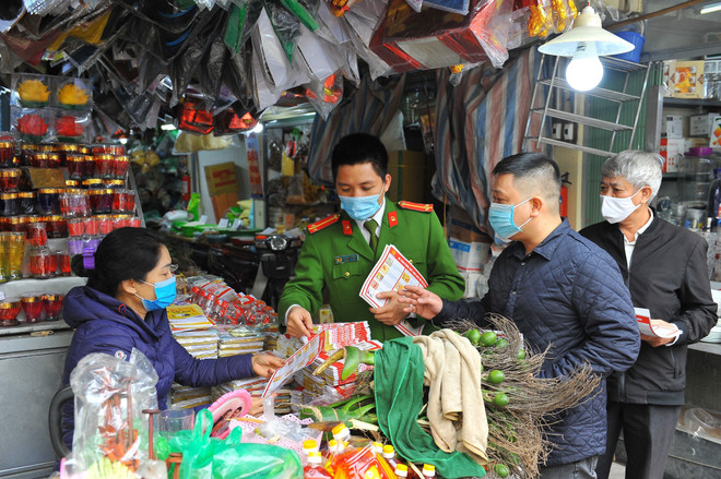 Trung úy Vũ Ngọc Hoàng cùng Ban quản lý chợ Thái Hà phát tờ rơi tuyên truyền phòng, chống cháy nổ cho bà con tiểu thương. (Ảnh: Minh Đức/TTXVN) Người chiến sỹ trẻ và mong muốn giản dị là luôn “thất nghiệp” ảnh 2