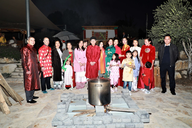 Đại sứ Lý Đức Trung cùng phu nhân và đồng bào quây quần bên nồi bánh chưng. (Ảnh: Văn Ứng/TTXVN) Xuân Quý Mão 2023: Tái hiện không gian Tết xưa ở Israel ảnh 2