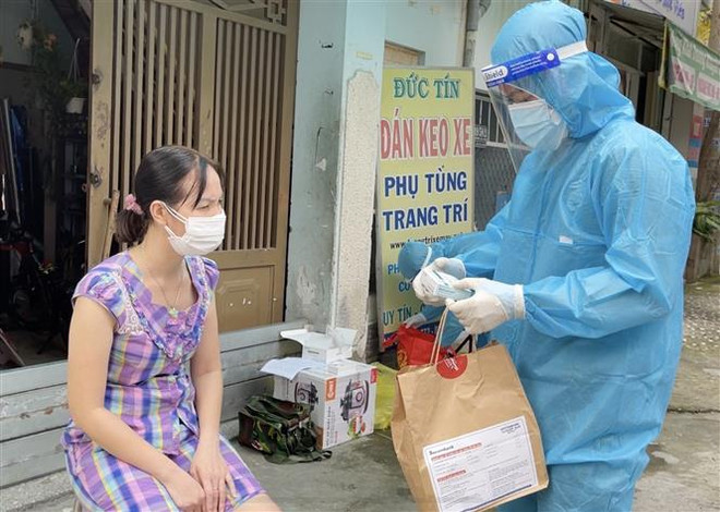 Nhân viên y tế trạm y tế lưu động phường 25, quận Bình Thạnh cấp phát túi thuốc cho F0 điều trị tại nhà. (Ảnh: Đinh Hằng/TTXVN) Ngành y tế TP.HCM tri ân các lực lượng hỗ trợ chống dịch COVID-19 ảnh 2