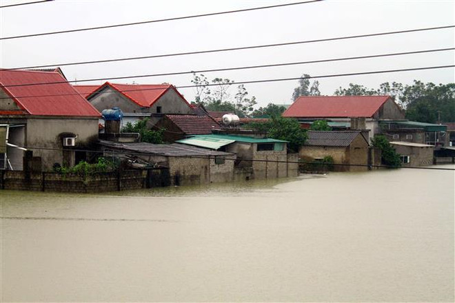 Nhiều nhà dân ngoài đê sông Lam tại huyện Hưng Nguyên (Nghệ An) bị ngập nặng do nước sông Lam đang lên cao trên mức báo động 2. (Ảnh: Tá Chuyên/TTXVN) “Lũ chồng lũ, bão chồng bão” miền Trung: Đặc điểm và cách chế ngự ảnh 2