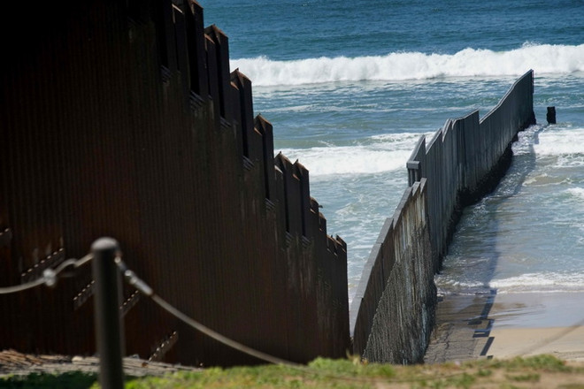Hàng rào ngăn cách giữa Mexico và Mỹ, đoạn qua San Ysidro, California, Mỹ. (Nguồn: AFP/TTXVN) Hàng trăm nghìn người tị nạn Trung Mỹ bị đối xử bất công tại Mỹ ảnh 1