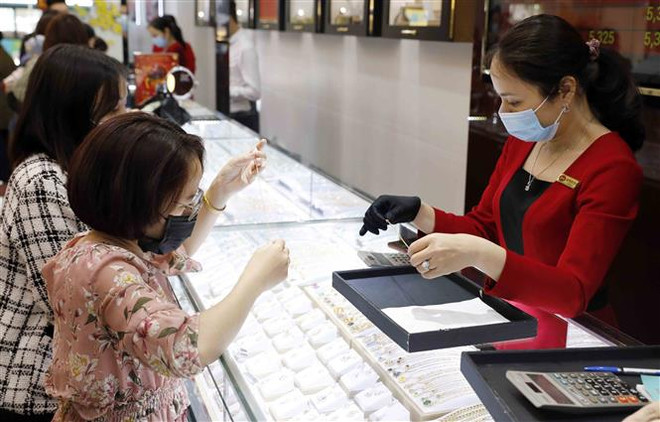 Mua bán vàng tại Công ty kinh doanh vàng bạc Mạnh Hải, phố Hoàng Cầu, Hà Nội. (Ảnh: Trần Việt/TTXVN) Khả năng đồng USD tăng kéo giá vàng trong nước giảm mạnh thời gian tới ảnh 1