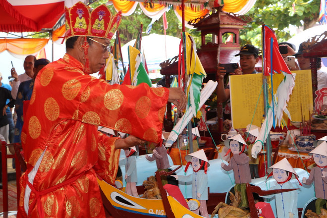 Thầy pháp hành lễ bỏ gạo vào các thuyền câu thế nhân trong Lễ Khao lề thế lính Hoàng Sa ở Quảng Ngãi. (Ảnh: Đinh Hương/TTXVN) TTXVN_2404khaolethelinhHoangSa3.jpg