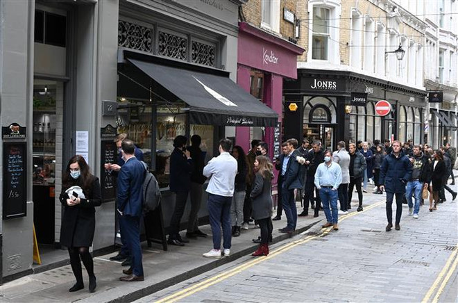 Người dân xếp hàng mua đồ bên ngoài một cửa hàng ở London (Anh), ngày 29/4/2021. (Ảnh: AFP/TTXVN) Lạm phát tại Anh tăng lên mức cao kỷ lục trong 30 năm qua ảnh 1