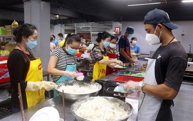 Nhóm thiện nguyện Tâm Lành nấu cơm, chế biến thức ăn hàng ngày hỗ trợ các lực lượng phòng chống dịch. (Ảnh: Lê Huy Hải/TTXVN) Những bếp cơm thiện nguyện đang đỏ lửa trong dịch COVID-19 ảnh 2
