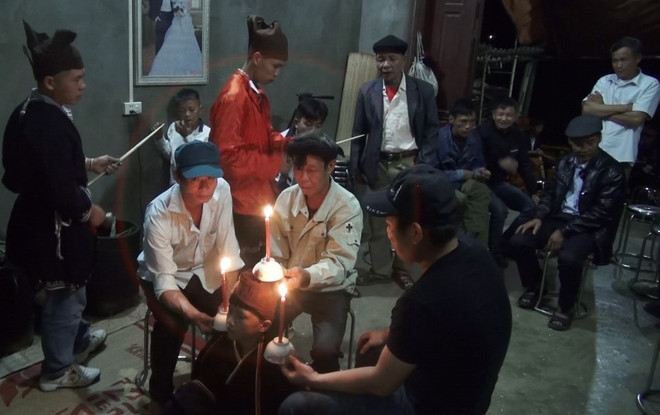 Đúng 1 giờ đêm đầu tiên của lễ, đứa trẻ mặc bộ trang phục của người dân tộc Dao Tiền và ngồi giữa 2 thầy mo. Họ đốt 3 cây nến, đặt lên 2 vai và đầu đứa trẻ vừa cúng, vừa nhẩy chèo để mời ma rừng, tổ tiên về chứng giám. (Ảnh: Vũ Hà/TTXVN) Độc đáo nghi lễ Lập Tĩnh - lễ đặt tên của người Dao Tiền ảnh 2