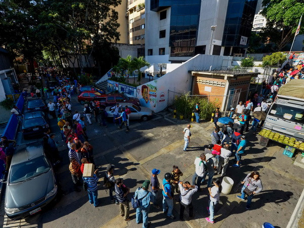 Người dân Venezuela xếp hàng chờ đổi tiền bên ngoài ngân hàng trung ương ở Caracas ngày 16/12. (Nguồn: AFP/TTXVN) Venezuela kéo dài thời hạn ngừng lưu hành đồng tiền mệnh giá lớn nhất ảnh 1