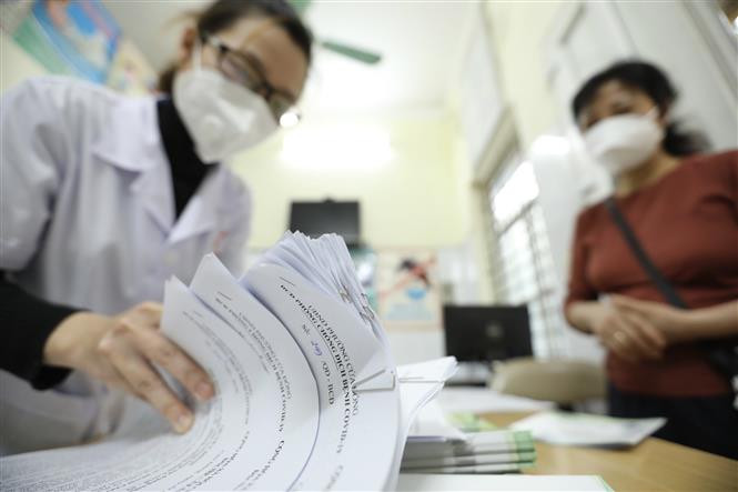 Giấy chứng nhận khỏi COVID-19 được trạm y tế phường thông báo cho tổ trưởng tổ dân phố đến nhận và phát tại nhà cho các bệnh nhân F0 khỏi bệnh. (Ảnh: Minh Quyết/TTXVN)