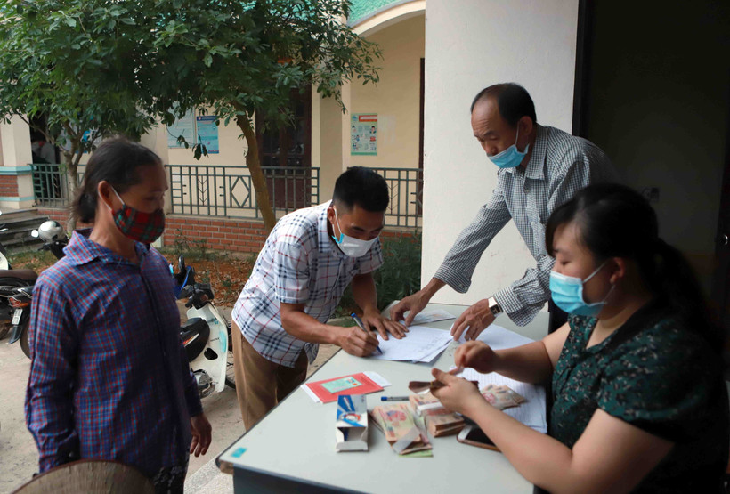 Chi trả tiền hỗ trợ cho hộ nghèo. (Ảnh minh họa: Hoàng Hùng/TTXVN)