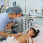 Nhân viên y tế Bệnh viện Nhi đồng 1 Thành phố Hồ Chí Minh chăm sóc bệnh nhi mắc tay chân miệng. (Ảnh: Đinh Hằng/TTXVN)