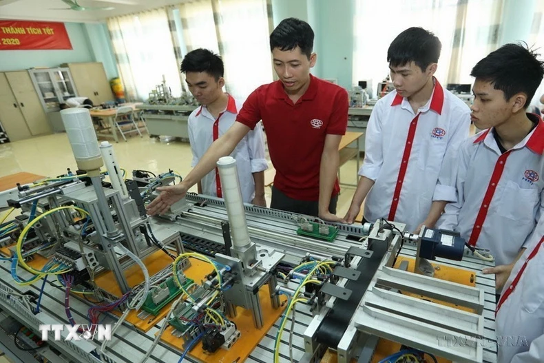 Thầy giáo giới thiệu mô hình tự động hoá cho sinh viên lớp điện tử công nghiệp tại một trường cao đẳng nghề công nghệ cao. (Ảnh: Hoàng Hiếu/TTXVN)