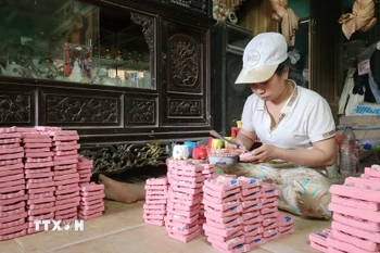 Trang trí tượng Tam vị Táo quân phù hợp thị hiếu khách hàng dịp Tết. (Ảnh: Võ Văn Dũng/TTXVN)