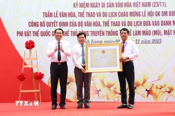 Lãnh đạo Sở Văn hóa, Thể thao và Du lịch tỉnh Vĩnh Long đón nhận Bằng chứng nhận di sản văn hóa phi vật thể quốc gia với nghề làm mão, mặt nạ của đồng bào Khmer. (Ảnh: Thanh Hòa/TTXVN)