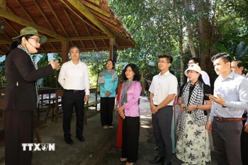 Đồng chí Ngô Đông Hải, Phó Trưởng Ban Tuyên giáo và Dân vận Trung ương (áo trắng, đứng thứ 2 từ trái sang) cùng các đại biểu tham quan nhà phục dựng khu làm việc của các đồng chí lãnh đạo Trung ương Cục miền Nam thời kháng chiến. (Ảnh: Thanh Tân/TTXVN)