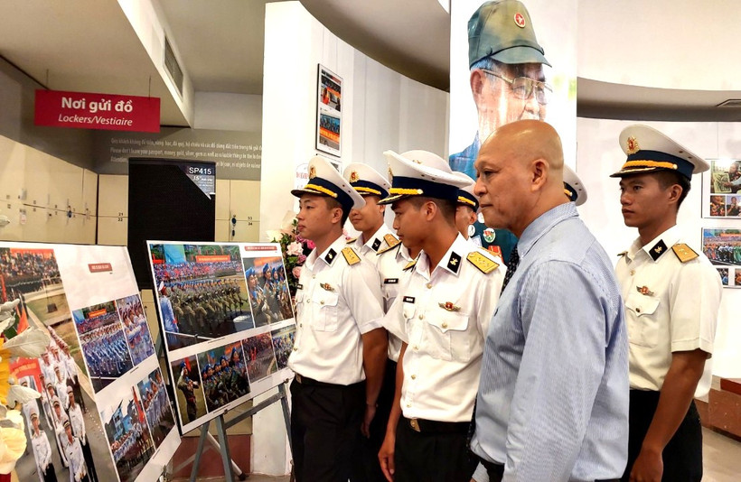 Nhiếp ảnh gia Nguyễn Á cùng các chiến sỹ hải quân tham quan triển lãm. (Ảnh: Minh Thu/Vietnam+)