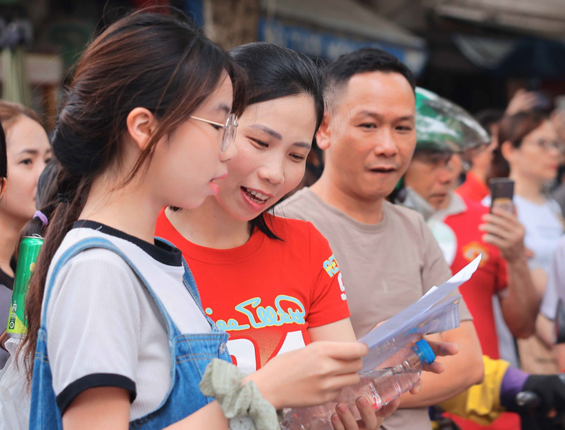 Phụ huynh, thí sinh xem lại bài sau khi rời phòng thi. (Ảnh: TTXVN) 