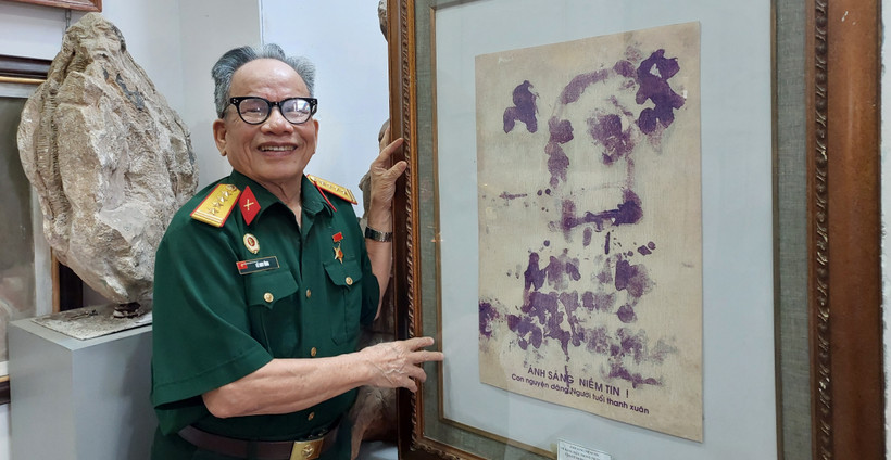 Họa sỹ Lê Duy Ứng và phiên bản của bức chân dung Bác Hồ vẽ bằng máu. (Ảnh: Minh Thu/Vietnam+)