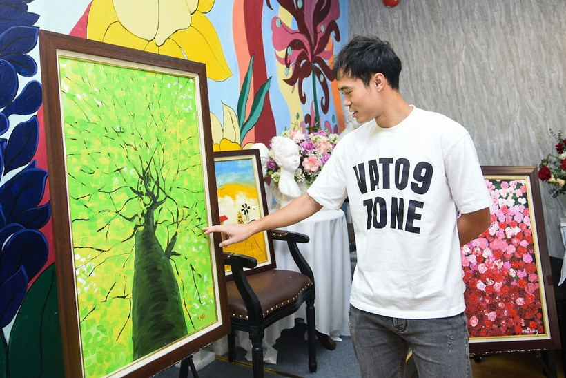 Văn Toàn ấn tượng với những bức tranh của trẻ tự kỷ. (Ảnh: PV/Vietnam+) 