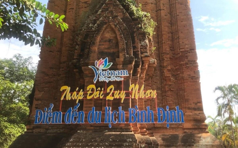 Tháp Đôi bị khoan vào tường gạch, bắt vít sắt thép để gắn biển giới thiệu tên di tích. (Ảnh: TTXVN)