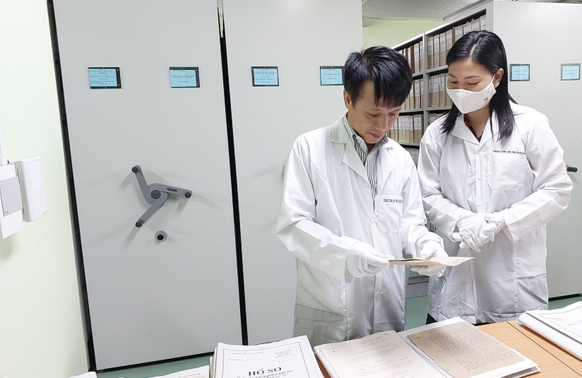 Anh Võ Thiết Cương, Trưởng phòng bảo quản (trái) cho phóng viên xem các trang tư liệu. (Ảnh: Minh Thu/Vietnam+)