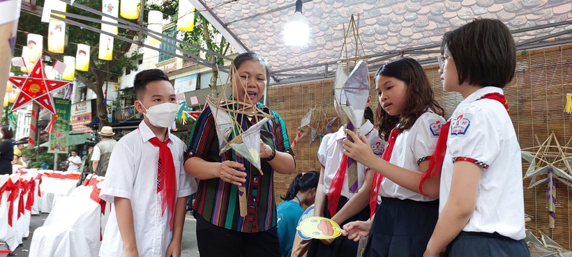 Bà Nguyễn Thị Tuyến ở Hoài Đức hướng dẫn các em thiếu nhi làm đèn ông sao. (Ảnh: Minh Thu/Vietnam+)